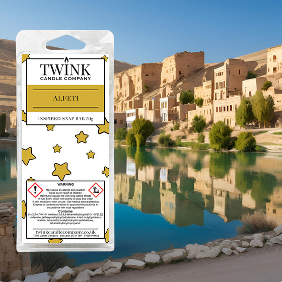 Alfeti inspired soy wax melt snap bar by Twink Candle Company, against a desert oasis with stone buildings and still water
