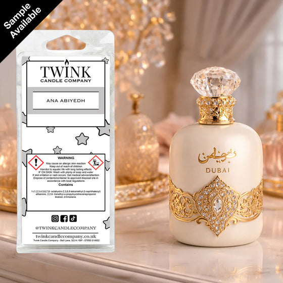 Ana Abiyedh inspired soy wax melt snap bar by Twink Candle Company, beside an ornate gold and white perfume bottle