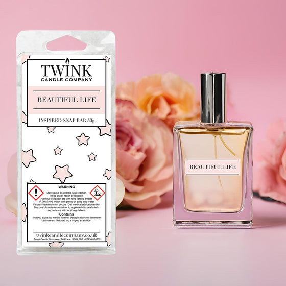 Beautiful Life inspired soy wax melt snap bar by Twink Candle Company, beside a perfume bottle and pink roses