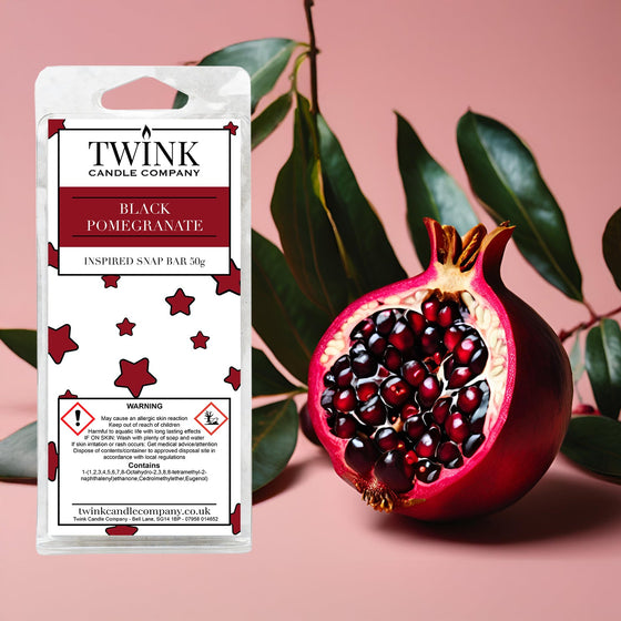 Black Pomegranate soy wax melt snap bar by Twink Candle Company, with a halved pomegranate and glossy leaves on pink