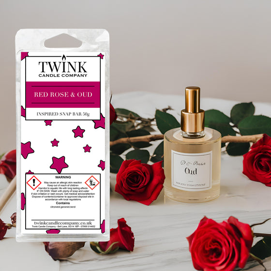 Red Rose & Oud inspired soy wax melt snap bar by Twink Candle Company, beside a perfume bottle and fresh red roses