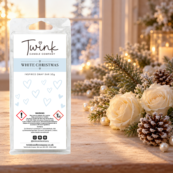 White Christmas inspired soy wax melt snap bar by Twink Candle Company, stood on a pale wood table beside snowy pine, white roses and a frosted pine cone