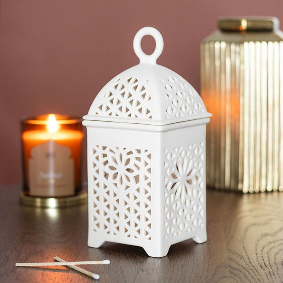 Lantern style wax and oil burner by Twink Candle Company, white ceramic lantern shown lit among candles
