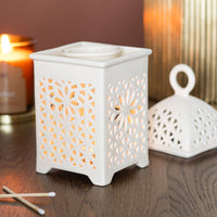 Lantern style wax and oil burner by Twink Candle Company, lit on a wooden table with candles