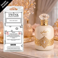 Ana Abiyedh inspired soy wax melt snap bar by Twink Candle Company, beside an ornate gold and white perfume bottle