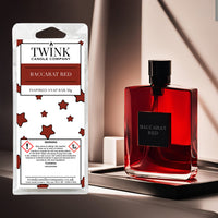 Baccarat Red soy wax melt snap bar by Twink Candle Company, beside a deep red perfume bottle on a dark polished surface