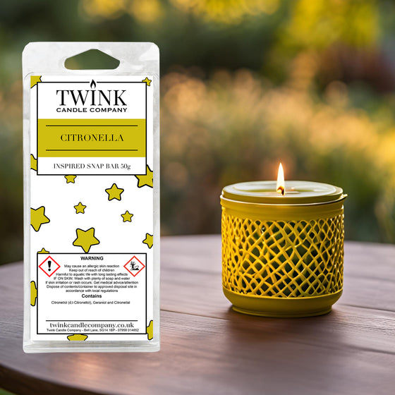 Citronella soy wax melt snap bar by Twink Candle Company, beside a lit candle in a yellow lattice holder on a garden table
