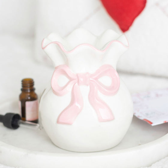 White ceramic wax/oil burner with a pink bow by Twink Candle Company