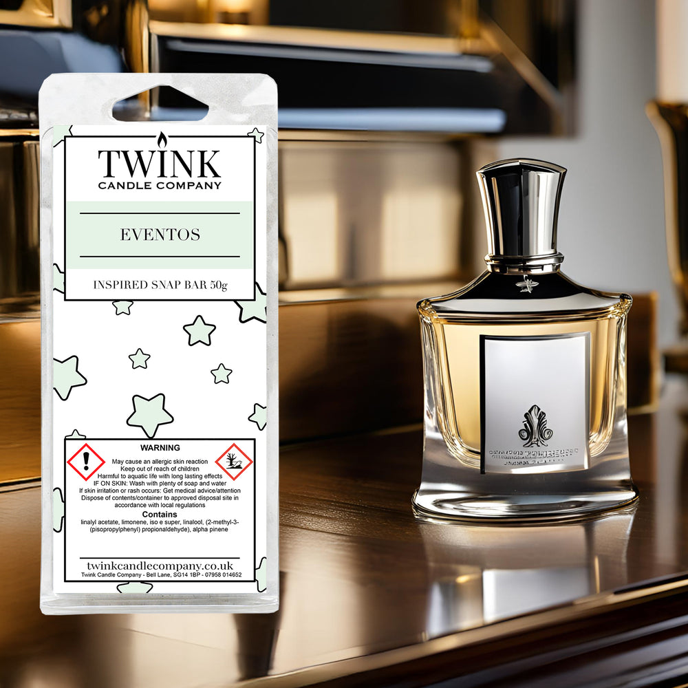 Eventos inspired soy wax melt snap bar by Twink Candle Company, beside a dark glass perfume bottle on a polished surface