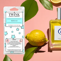 Nenuco soy wax melt snap bar by Twink Candle Company, with a lemon, green leaves and a cologne bottle on a pink background