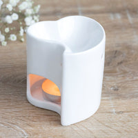 Mini heart wax and oil burner by Twink Candle Company, a white ceramic heart shown lit