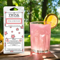 Pink Lemonade soy wax melt snap bar by Twink Candle Company, beside a tall glass of pink lemonade with an orange slice