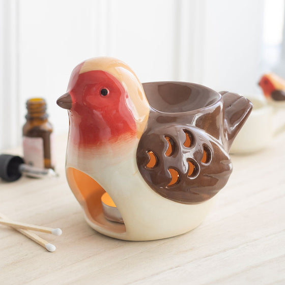 Robin wax and oil burner by Twink Candle Company, a ceramic robin with a red breast, shown lit with fragrance oils