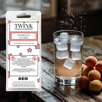 Sparkling Lychee inspired soy wax melt snap bar by Twink Candle Company, beside a glass of iced drink and fresh lychees
