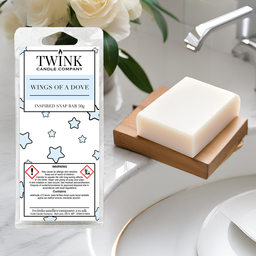 Wings Of A Dove soy wax melt snap bar by Twink Candle Company, beside a bar of white soap on a wooden dish by a basin