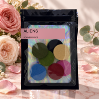Pack of 8 Aliens scented hoover discs in its sealed black foil packet beside pink roses and eucalyptus on pale marble