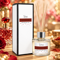 Baccarat Red reed diffuser by Twink Candle Company, a 100ml glass bottle with reeds beside its white gift box, on a pale wood surface with a cut-glass perfume bottle, saffron threads and a brass dish