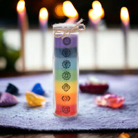 Chakra tube candle by Twink Candle Company, lit on a cloth with crystals and candles behind