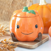 Cute smiling pumpkin wax/oil burner by Twink Candle Company on a wooden board