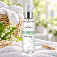 Fairy inspired room spray by Twink Candle Company, a 100ml bottle on folded white laundry with a willow basket, pegs and lily of the valley