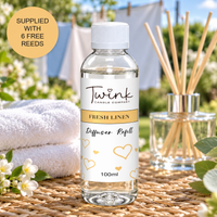 Fresh Linen reed diffuser refill by Twink Candle Company, a 100ml bottle on a rattan mat by a washing line of fresh laundry