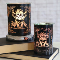Two highland cow black touch melters by Twink Candle Company, styled together on a stack of books