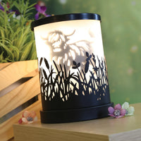Highland cow black shadow wax and oil burner by Twink Candle Company, lit on a table with flowers