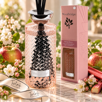 Woodbridge Summer Breeze 1000ml reed diffuser in a pink woven glass bottle with black reeds on pale marble, beside its pink gift box with apple blossom, apples and rhubarb, and a Twink Candle Company ribbon