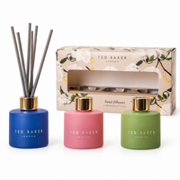Ted Baker gift set of three 50ml reed diffusers in blue, pink and green glass in front of the floral gift box on a plain white background