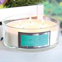 Woodbridge Country Garden 5-wick candle bowl lit and glowing on a table with flowers behind