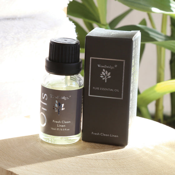 Woodbridge Fresh Clean Linen essential oil 15ml bottle and box styled on wood with a plant behind